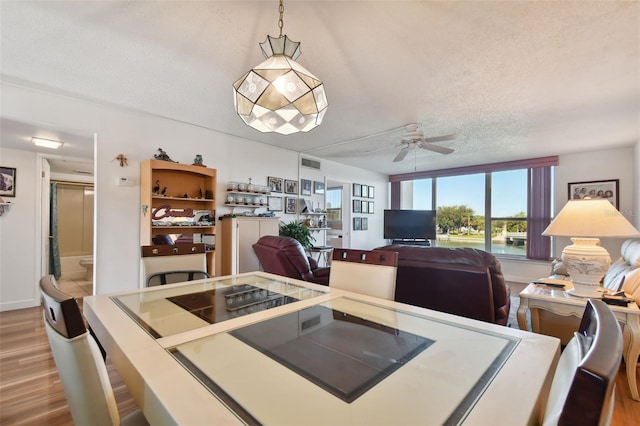 dining area with ceiling fan, a textured ceiling, and light wood-type flooring