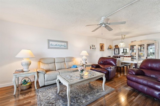 living room featuring a textured ceiling, ceiling fan, and dark wood-type flooring