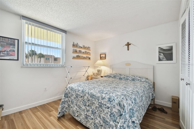 bedroom with a textured ceiling, hardwood / wood-style flooring, and a closet