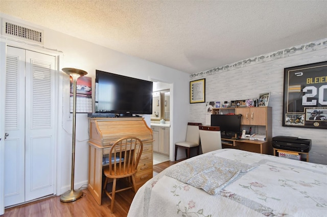 bedroom featuring a textured ceiling, light wood-type flooring, and ensuite bathroom