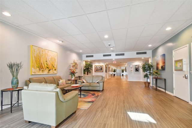 living room with a paneled ceiling and light wood-type flooring