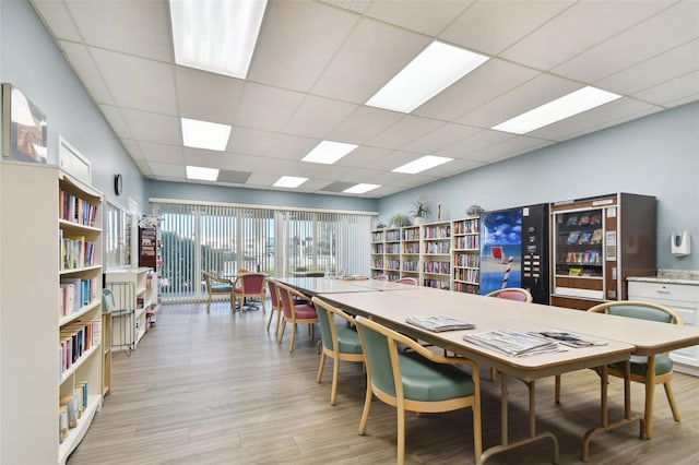 dining space featuring a drop ceiling and light hardwood / wood-style floors