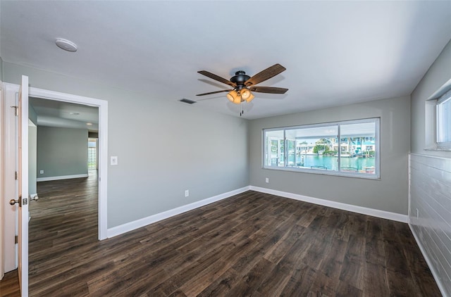 empty room with ceiling fan and dark hardwood / wood-style flooring