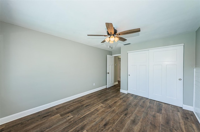 unfurnished bedroom with ceiling fan, dark wood-type flooring, and a closet