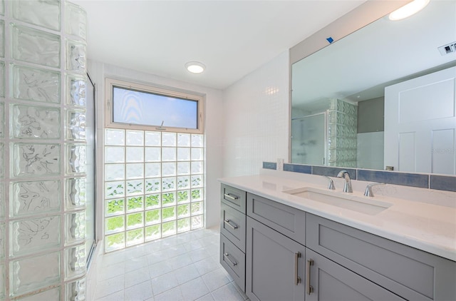 bathroom featuring tile patterned flooring, vanity, and a shower with shower door