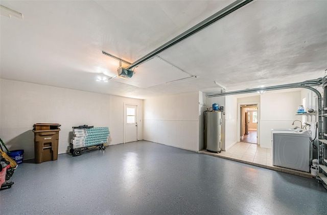 garage featuring washing machine and clothes dryer, a garage door opener, and water heater