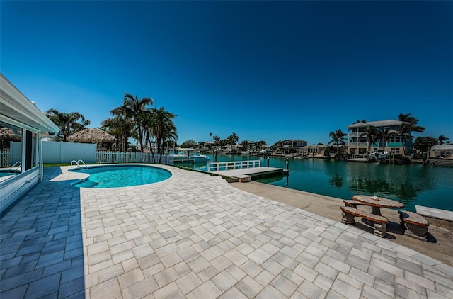 view of swimming pool with a boat dock, a patio area, and a water view