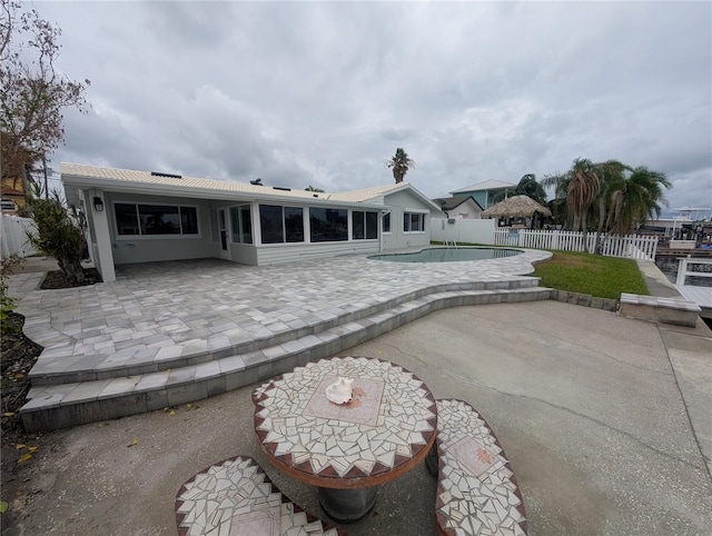 rear view of property featuring a patio, a fenced in pool, and a sunroom