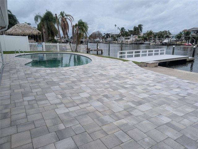 view of pool with a boat dock, a water view, and a patio