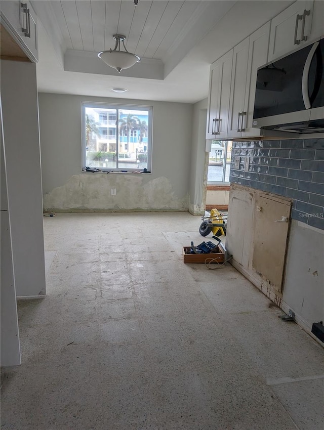 kitchen featuring a tray ceiling, tasteful backsplash, plenty of natural light, and white cabinets