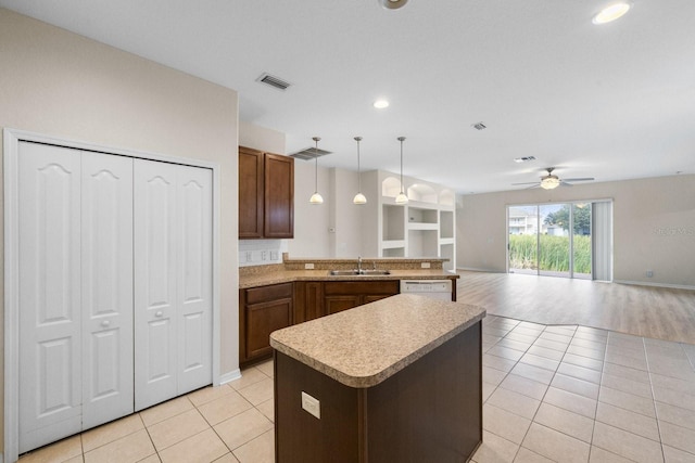 kitchen with light tile patterned floors, sink, ceiling fan, hanging light fixtures, and a kitchen island