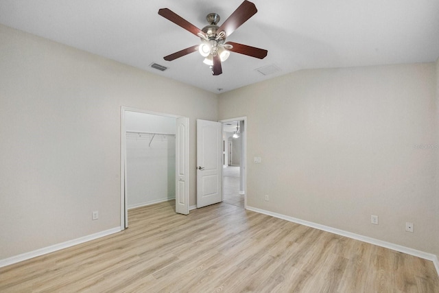 unfurnished bedroom featuring ceiling fan, lofted ceiling, a closet, and light wood-type flooring