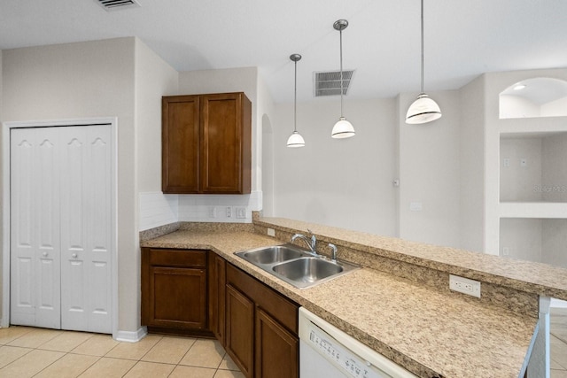 kitchen featuring pendant lighting, dishwasher, sink, light tile patterned floors, and kitchen peninsula