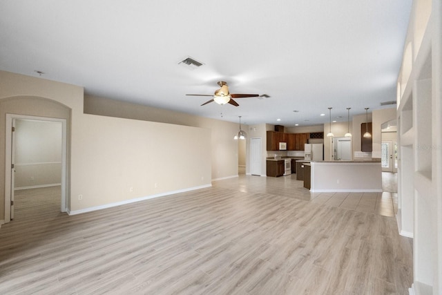 unfurnished living room featuring ceiling fan and light wood-type flooring