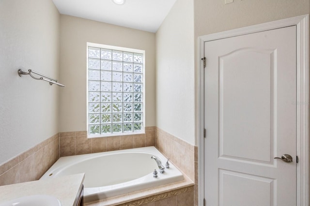 bathroom with tiled tub and vanity