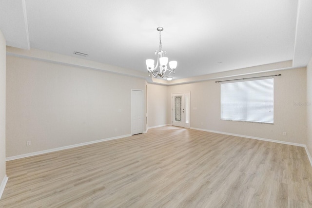 empty room with a chandelier and light hardwood / wood-style flooring