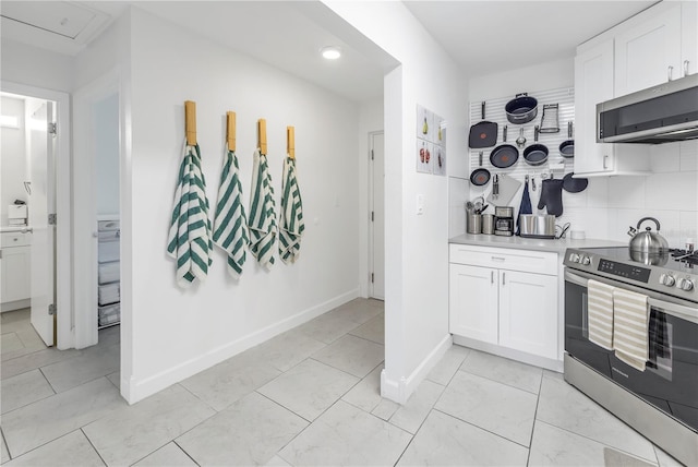 kitchen featuring backsplash, appliances with stainless steel finishes, white cabinetry, and light tile floors