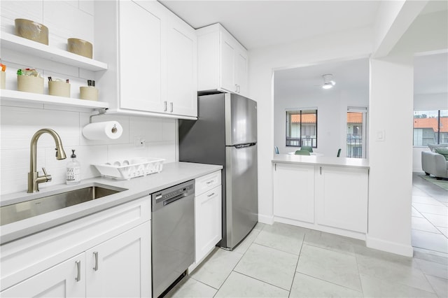 kitchen featuring tasteful backsplash, appliances with stainless steel finishes, white cabinetry, and light tile flooring