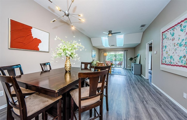 dining area featuring ceiling fan with notable chandelier, dark hardwood / wood-style flooring, and lofted ceiling with skylight