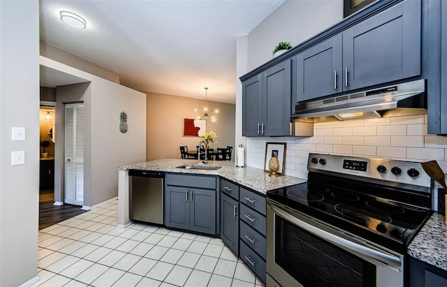 kitchen with decorative light fixtures, stainless steel appliances, light stone counters, and sink