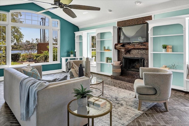 living room featuring lofted ceiling, ceiling fan, dark parquet flooring, ornamental molding, and a fireplace