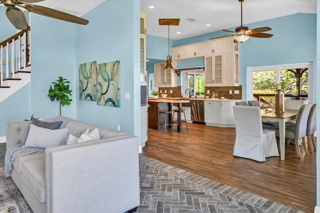 living room with dark wood-type flooring, ceiling fan, lofted ceiling, and sink