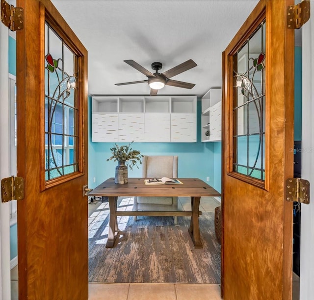 tiled office space featuring a textured ceiling and ceiling fan