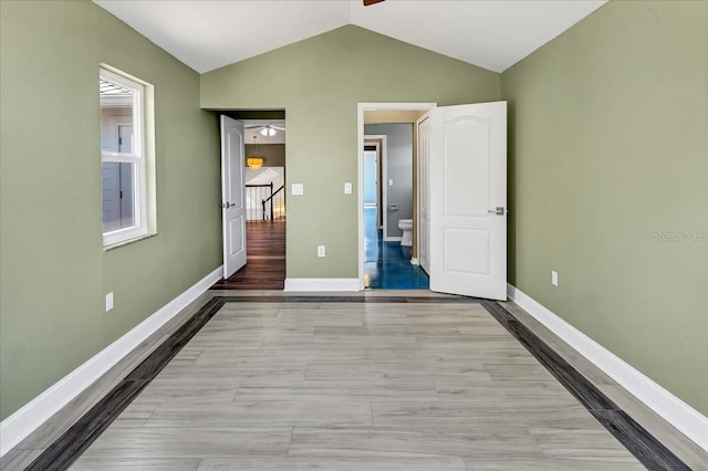 unfurnished bedroom with light hardwood / wood-style floors, lofted ceiling, and ensuite bath