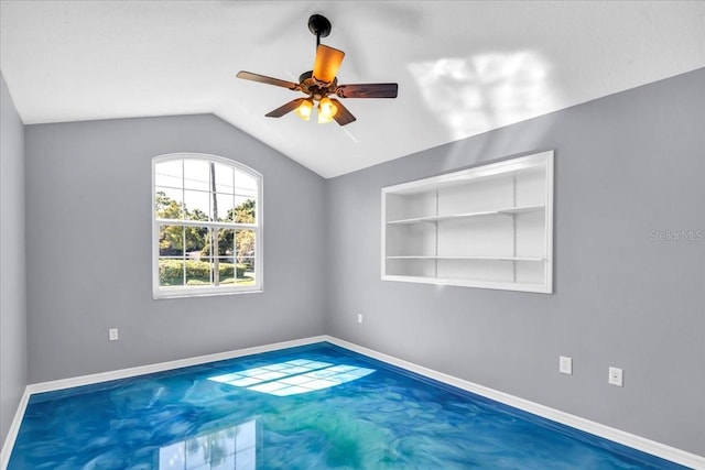 carpeted spare room with lofted ceiling, ceiling fan, and built in shelves