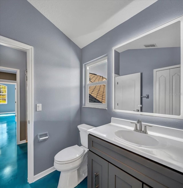 bathroom with toilet, lofted ceiling, and vanity