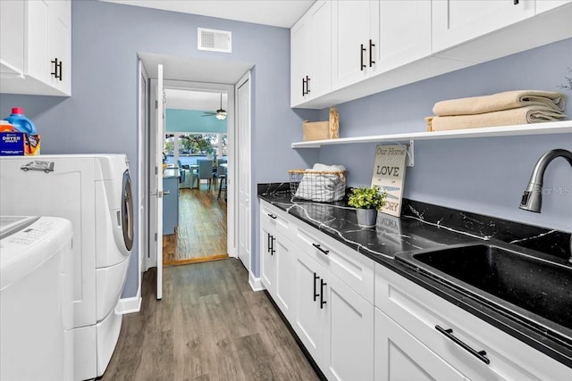 clothes washing area with sink, independent washer and dryer, dark hardwood / wood-style floors, and cabinets