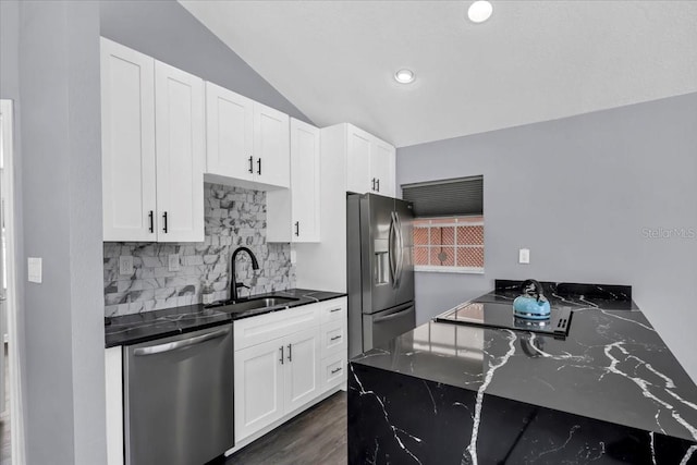 kitchen featuring sink, white cabinetry, stainless steel appliances, vaulted ceiling, and dark wood-type flooring