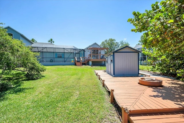 view of yard featuring an outdoor fire pit, a lanai, a shed, and a deck