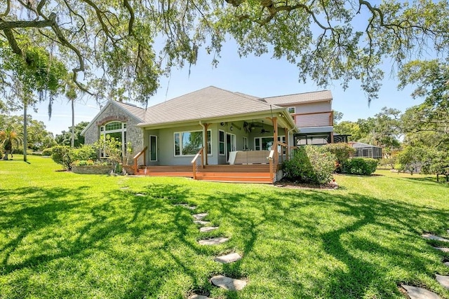 back of property with a wooden deck, a lawn, and ceiling fan