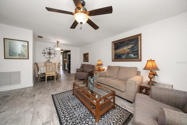 living room featuring light hardwood / wood-style flooring, ceiling fan, and a textured ceiling