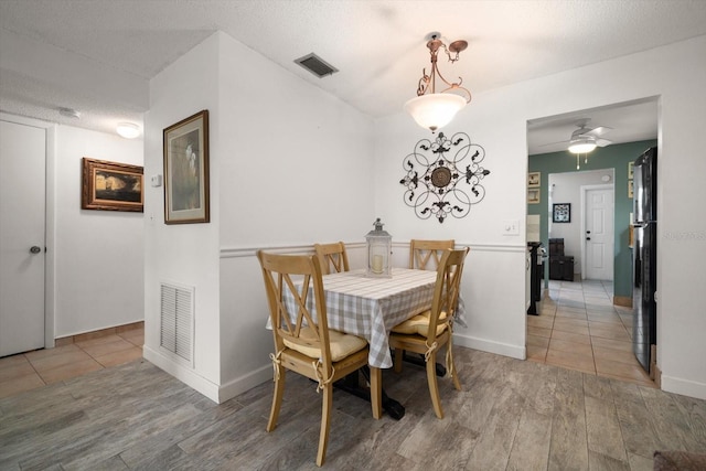 dining area with a textured ceiling, ceiling fan, and light wood-type flooring