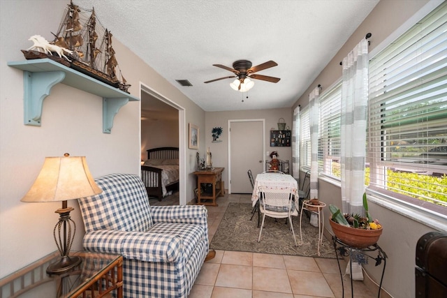 interior space with a textured ceiling, ceiling fan, and light tile floors