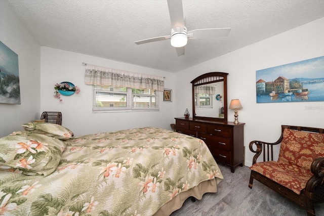 bedroom with light hardwood / wood-style floors, ceiling fan, and a textured ceiling