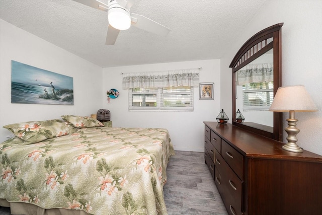 bedroom featuring ceiling fan, a textured ceiling, and multiple windows