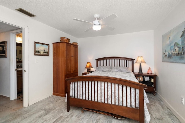 bedroom featuring a textured ceiling, ceiling fan, and light tile flooring