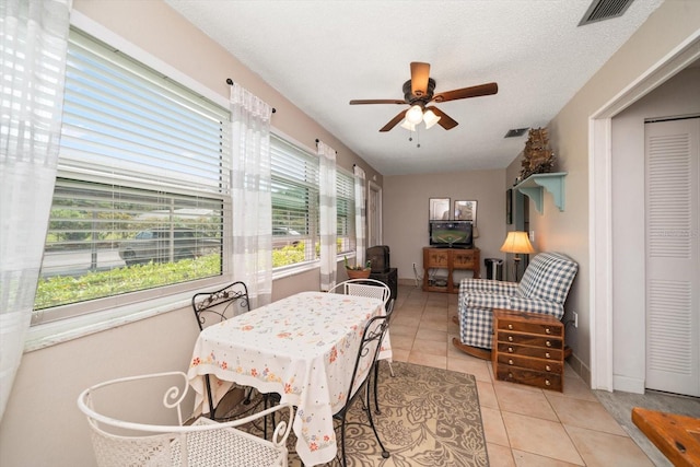 dining space with a textured ceiling, ceiling fan, and light tile floors