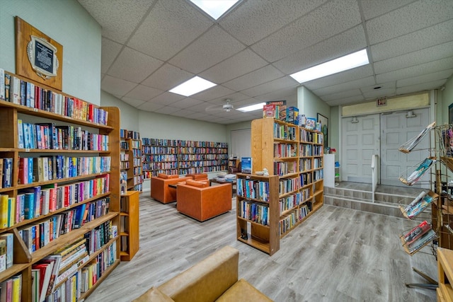 living area with a drop ceiling and light hardwood / wood-style floors