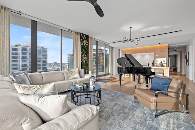 living room featuring ceiling fan with notable chandelier, hardwood / wood-style floors, and a wall of windows