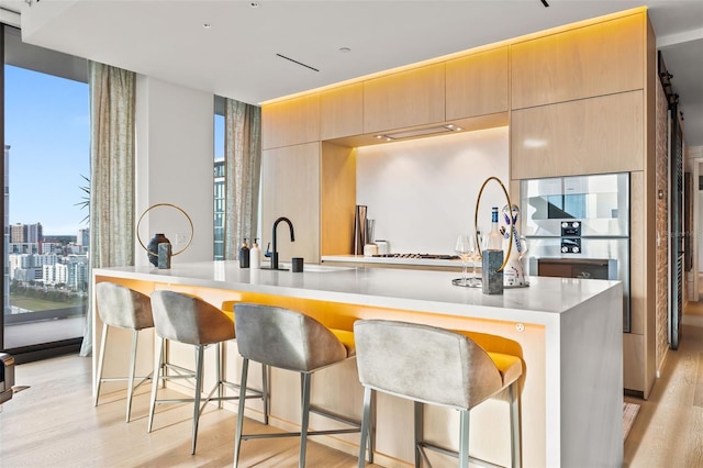 kitchen featuring a kitchen breakfast bar, sink, light hardwood / wood-style floors, and light brown cabinets