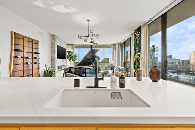 kitchen with floor to ceiling windows, a notable chandelier, sink, and pendant lighting