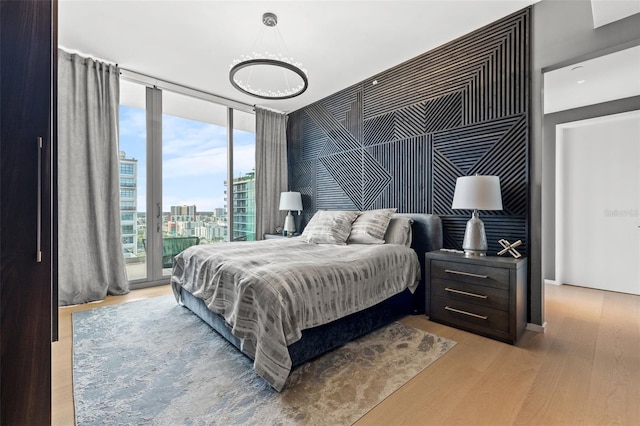 bedroom with floor to ceiling windows, light hardwood / wood-style flooring, a notable chandelier, and access to exterior