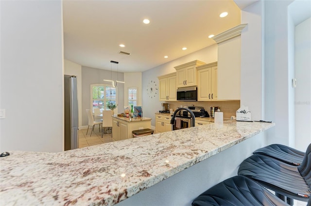 kitchen featuring hanging light fixtures, a breakfast bar, light stone countertops, appliances with stainless steel finishes, and light tile floors