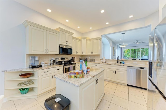 kitchen with appliances with stainless steel finishes, light stone countertops, backsplash, and light tile floors