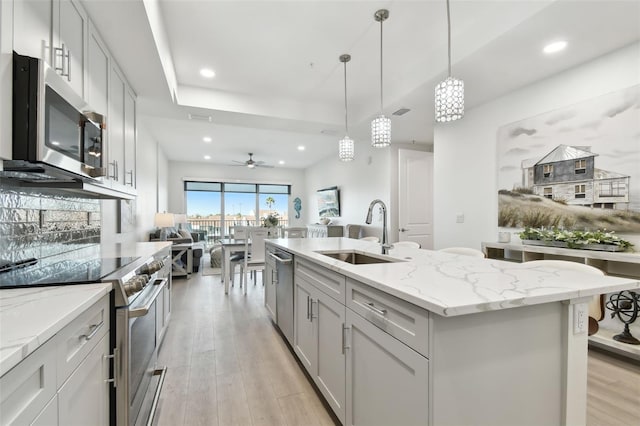 kitchen with open floor plan, light wood-type flooring, recessed lighting, stainless steel appliances, and a sink