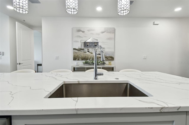 kitchen featuring a sink, visible vents, light stone countertops, and recessed lighting